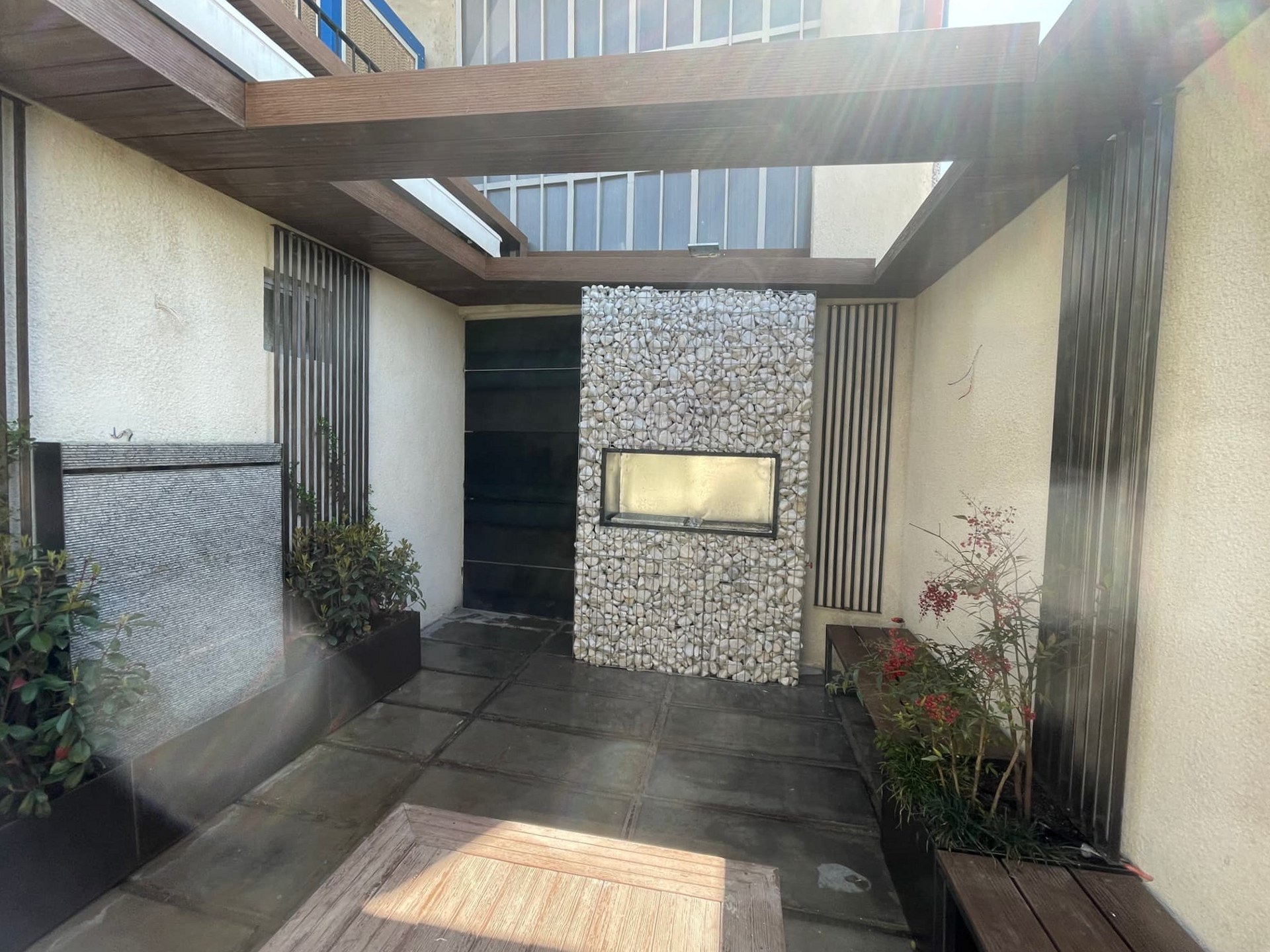 Gabion wall with a light opening and wall water feature in the factory courtyard